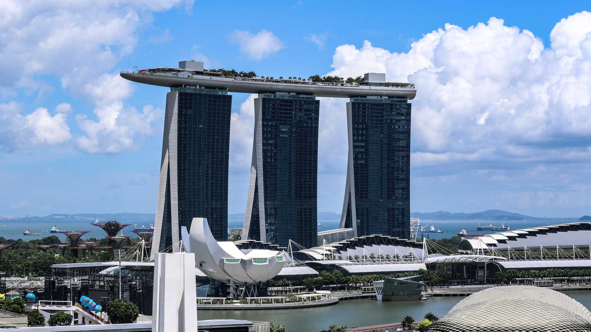 The 55-storey Marina Bay Sands hotel consisting of 3 towers with an infinity pool looking like a ship sailing above them.