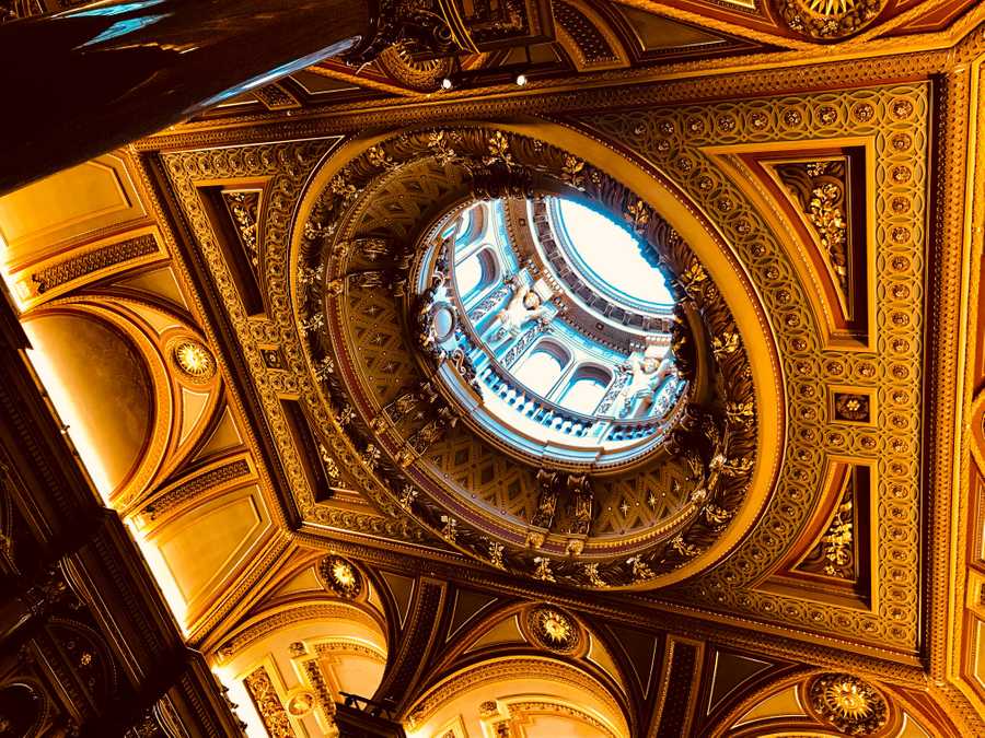 An ornate wooden ceiling at the Fitzwilliam Museum is decorated in gold details.