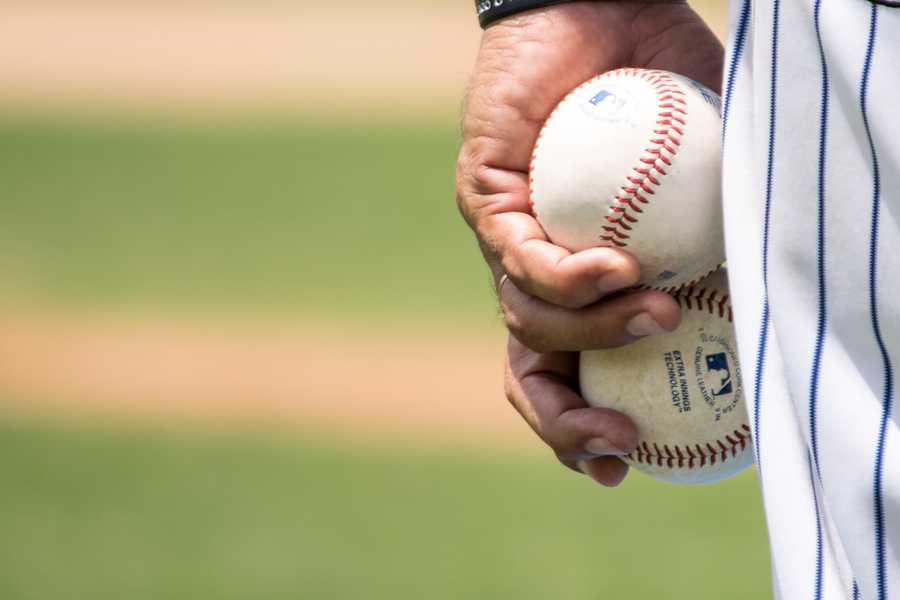 A close up of a baseball players hand holding baseballs.