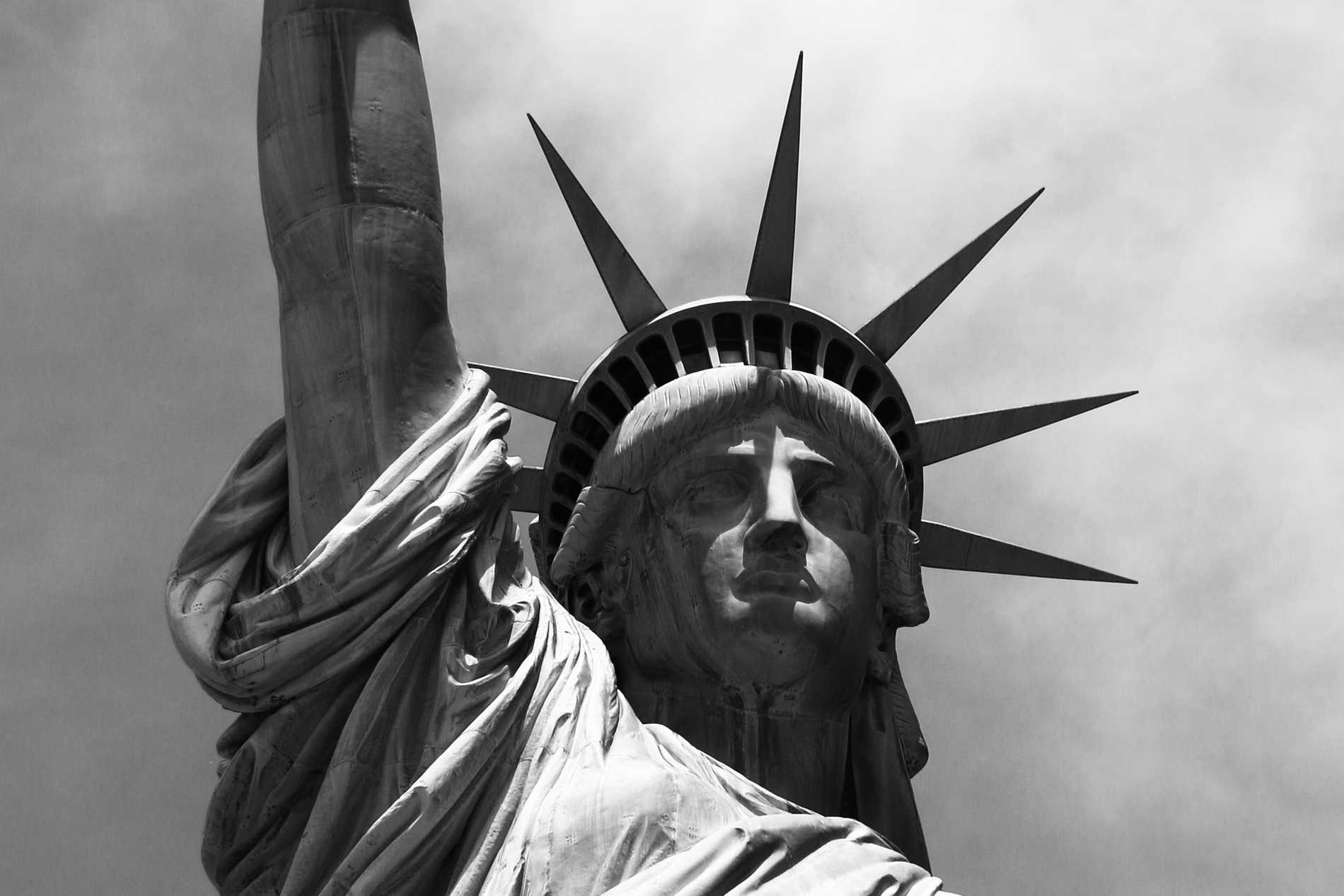A grayscale close-up of the Statute of Liberty's face and crown.